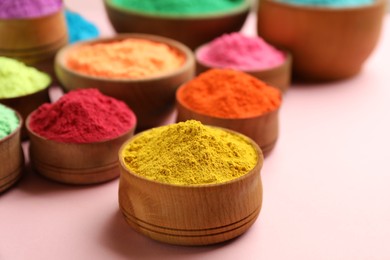 Photo of Colorful powders in wooden bowls on pink background. Holi festival celebration