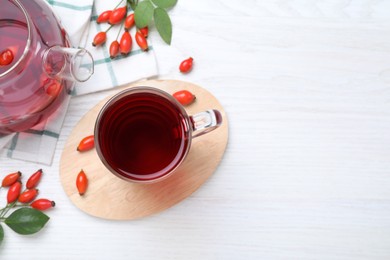 Flat lay composition with aromatic rose hip tea on white wooden table. Space for text