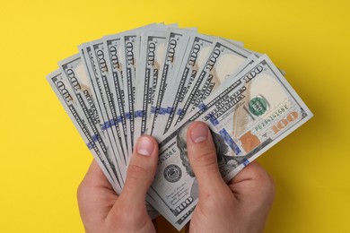 Photo of Money exchange. Man holding dollar banknotes on yellow background, top view