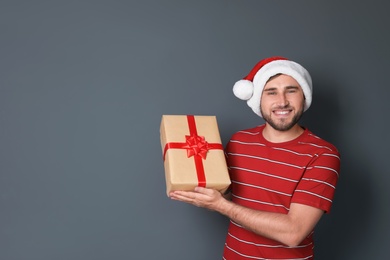 Photo of Young man with Christmas gift on grey background