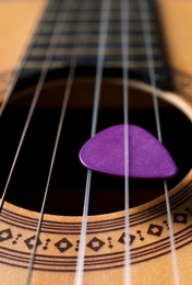 Photo of Closeup view of acoustic guitar, focus on sound hole with plectrum