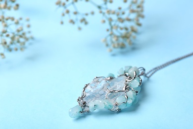 Photo of Beautiful silver necklace with pure quartz gemstones on light blue background. Space for text