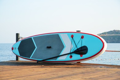 SUP board with paddle on wooden pier near sea