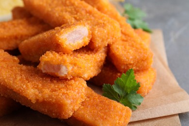 Photo of Fresh breaded fish fingers on parchment, closeup