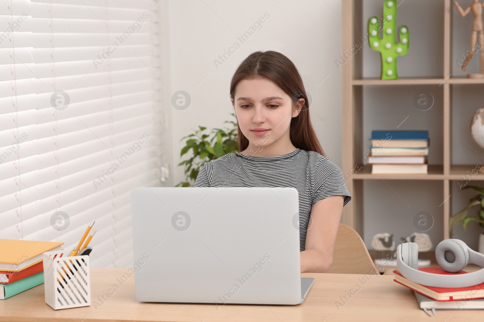 Photo of Cute girl using laptop at desk in room. Home workplace