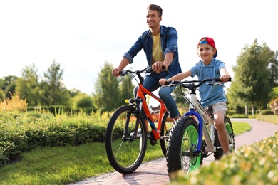 Dad and son riding modern bicycles outdoors