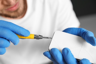 Technician repairing mobile phone with screwdriver, closeup