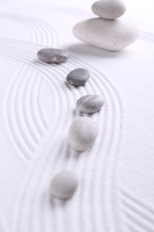 Photo of Zen garden stones on white sand with pattern, closeup