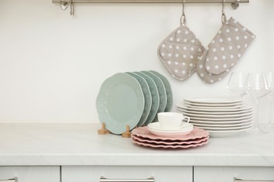 Photo of Clean plates, glasses and cup on white marble countertop in kitchen, space for text