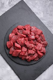 Pieces of raw beef meat on grey textured table, top view