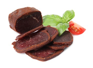 Photo of Delicious dry-cured beef basturma with basil and tomato on white background