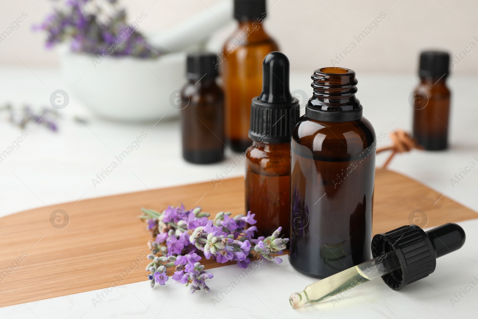Photo of Bottles with natural lavender essential oil on wooden board. Space for text