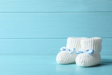 Handmade baby booties on table against wooden background. Space for text