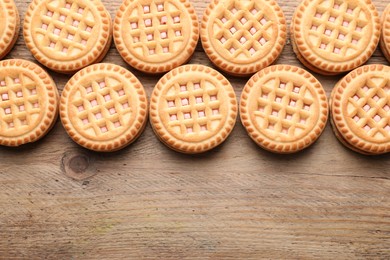 Tasty sandwich cookies with cream on wooden table, flat lay. Space for text