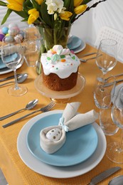 Photo of Festive table setting with painted eggs, traditional Easter cake and vase of tulips