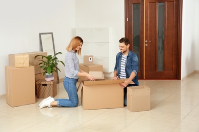 Happy couple unpacking moving box in their new house