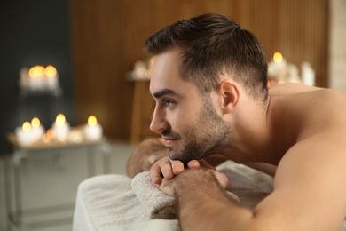 Handsome man relaxing on massage table in spa salon