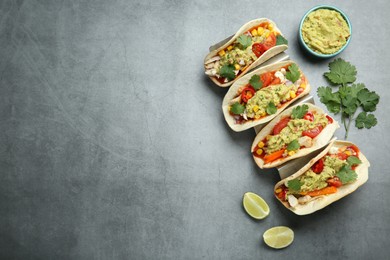 Photo of Delicious tacos with guacamole, meat and vegetables served on grey table, flat lay. Space for text