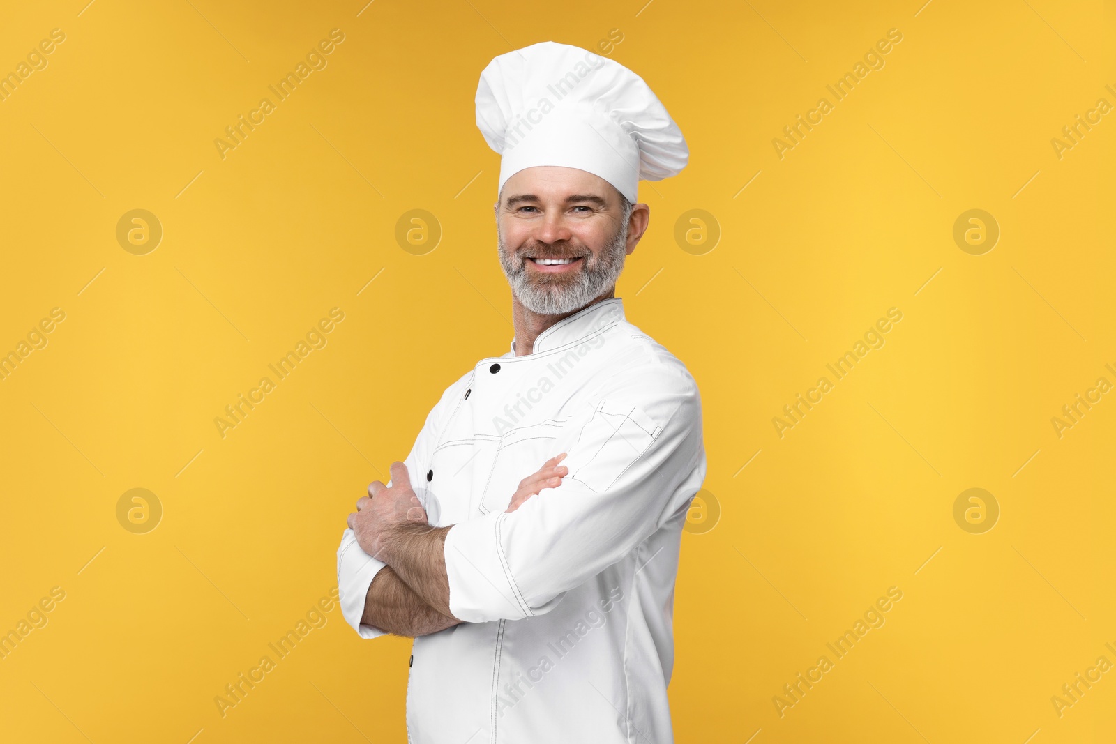 Photo of Happy chef in uniform on orange background