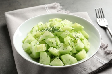 Photo of Delicious cucumber salad with dill in bowl served on grey table