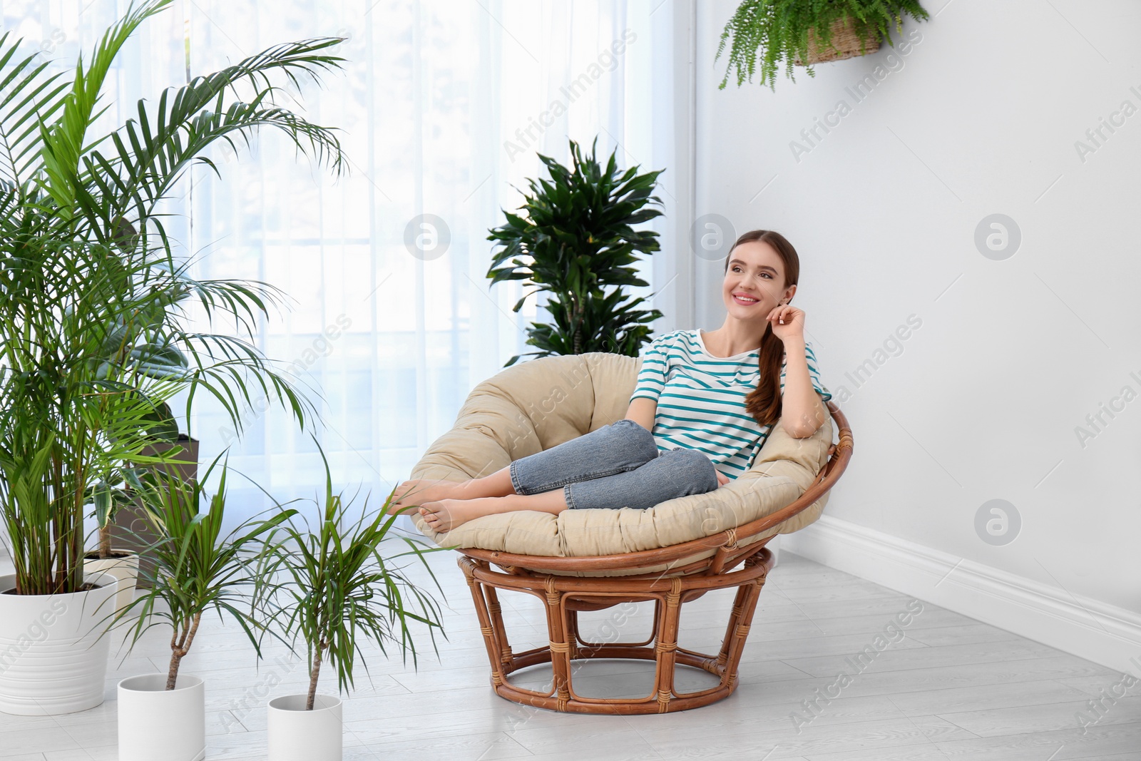 Photo of Young woman in room decorated with plants. Home design