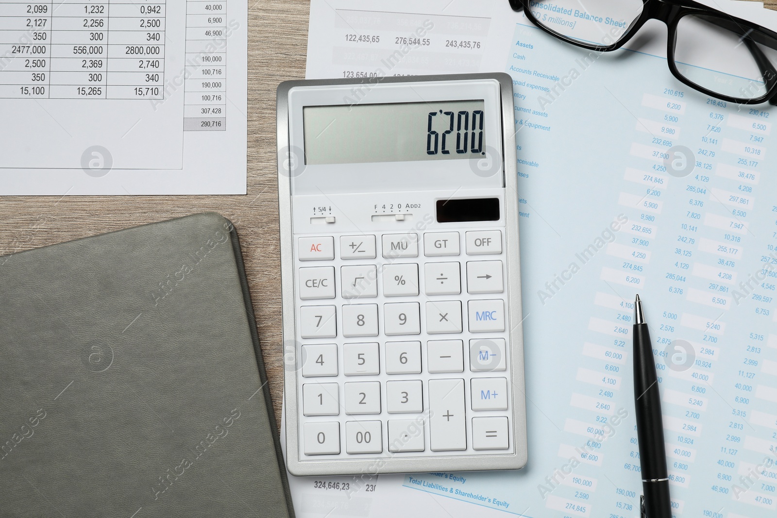 Photo of Calculator, notebook, glasses and documents on wooden table, flat lay