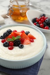 Photo of Delicious semolina pudding with berries on white marble table