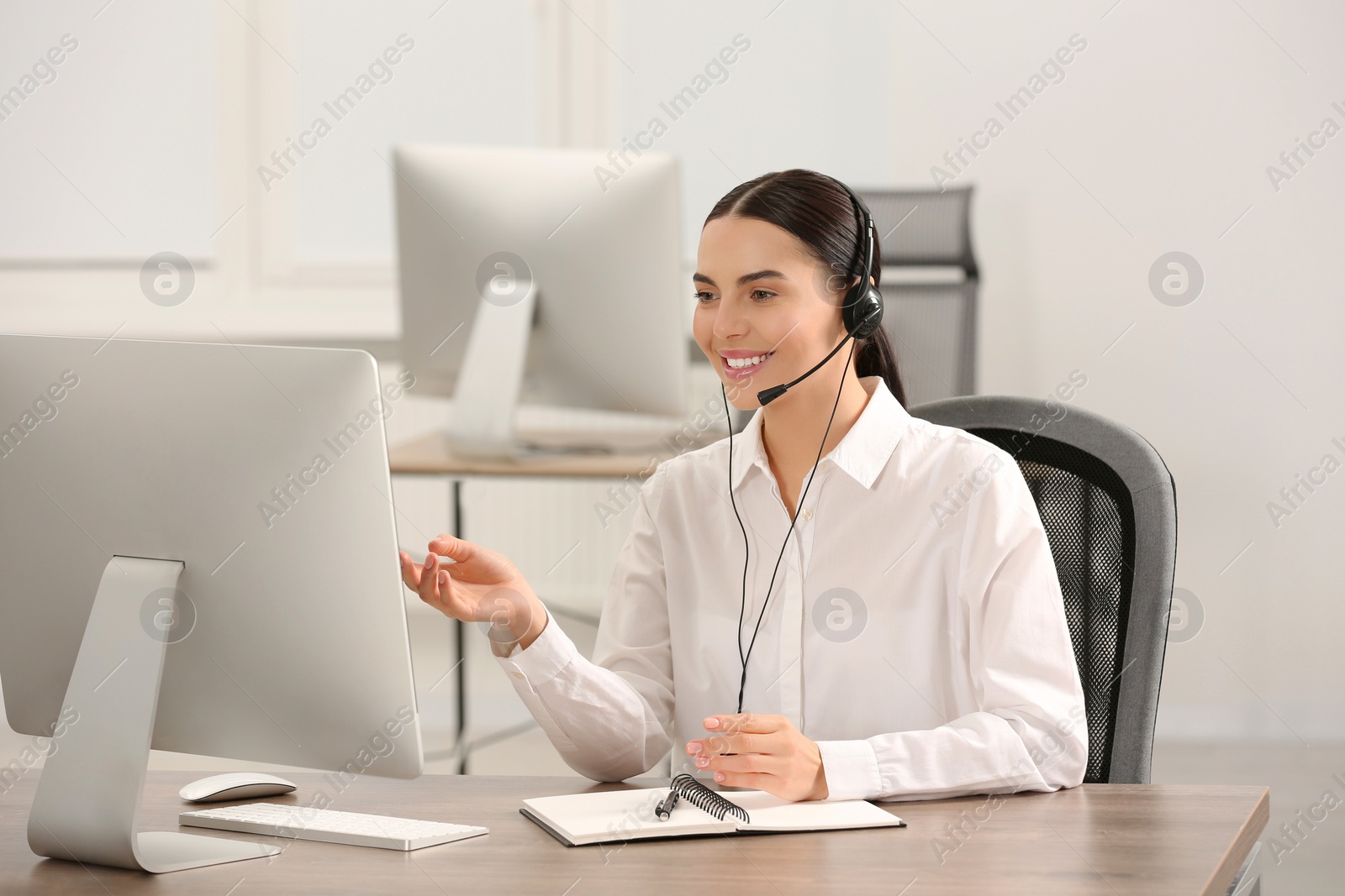 Photo of Hotline operator with headset and notebook working in office