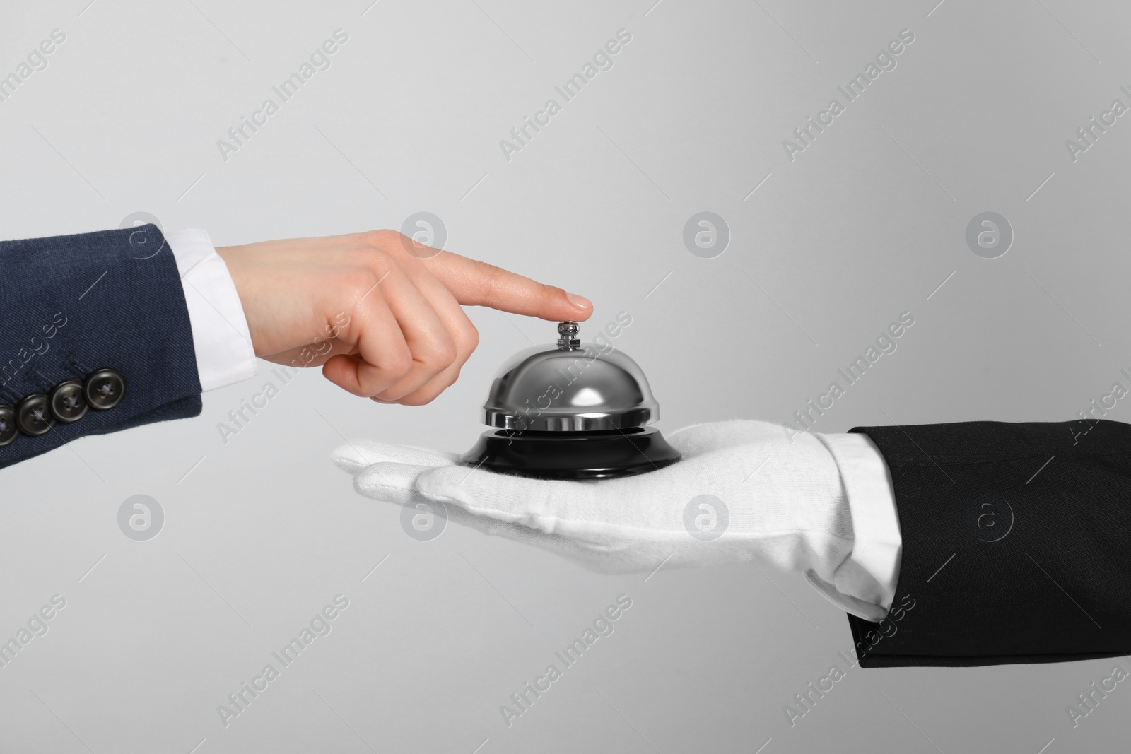 Photo of Man ringing butler service bell on grey background, closeup