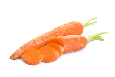 Whole and sliced ripe carrots on white background