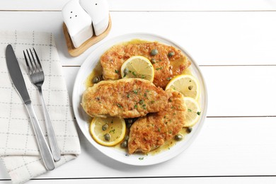 Photo of Delicious chicken piccata served on white wooden table, flat lay