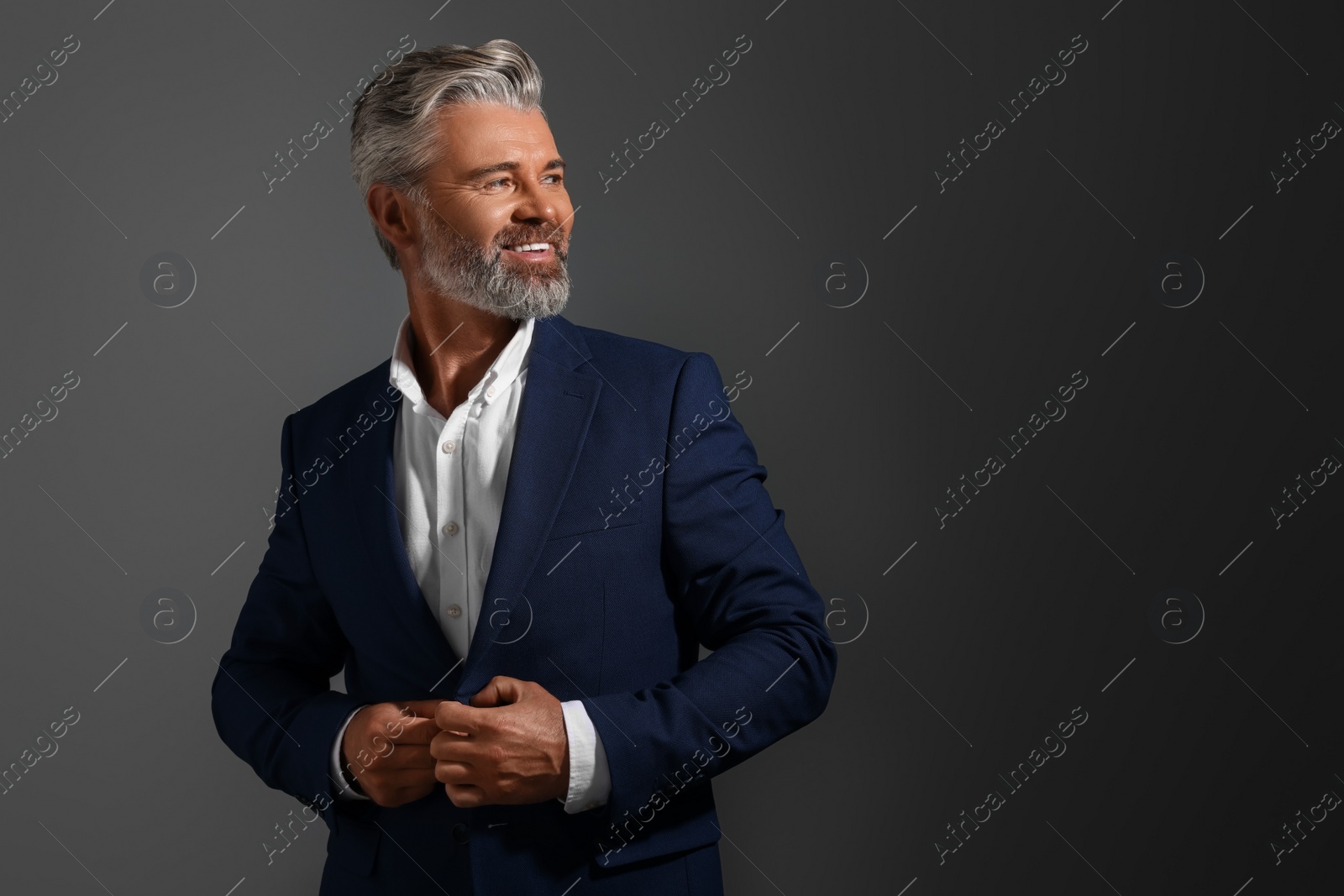Photo of Portrait of smiling man with beautiful hairstyle on dark background. Space for text