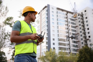 Builder operating drone with remote control at construction site. Aerial photography