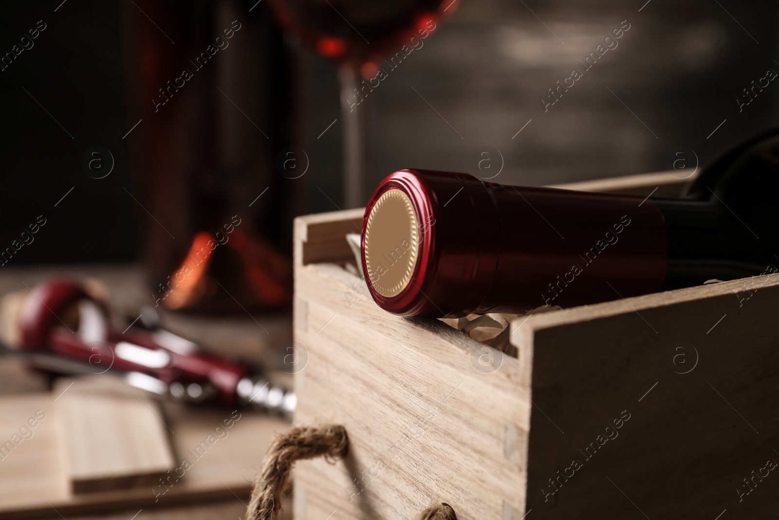 Photo of Open wooden crate with bottle of wine on blurred background