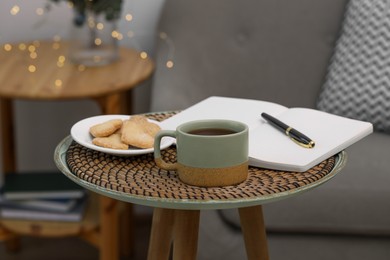 Photo of Cup of drink, cookies and notebook on coffee table indoors