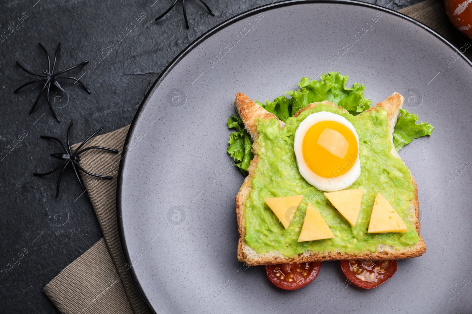 Photo of Halloween themed breakfast served on black table, flat lay. Tasty sandwich with fried egg