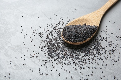 Photo of Spoon with poppy seeds on grey background