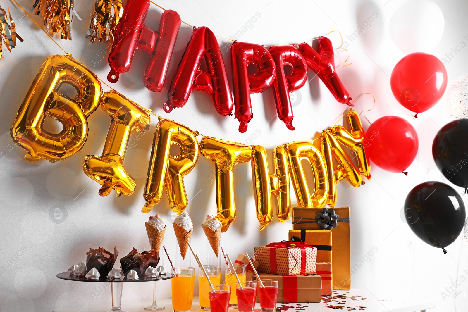 Photo of Treats and gifts on table in room decorated for birthday party with different balloons