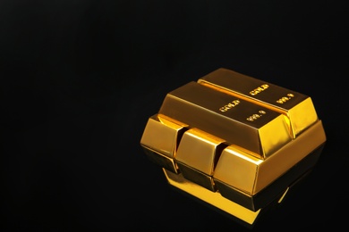 Photo of Stack of shiny gold bars on black background. Space for text