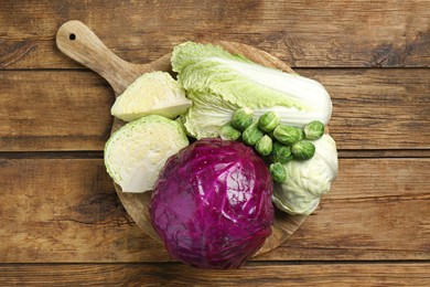 Different types of cabbage on wooden table, top view