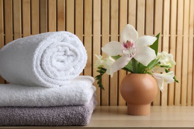 Photo of Terry towels and beautiful flowers on wooden table