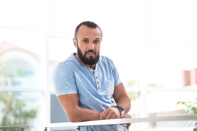 Photo of Portrait of handsome mature man leaning on handrail indoors