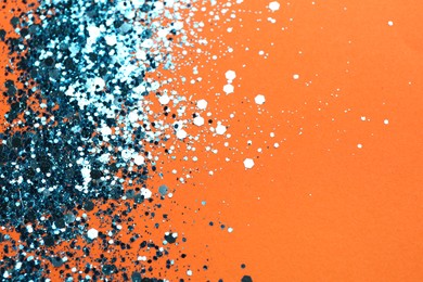 Photo of Shiny bright blue glitter on orange background. Space for text