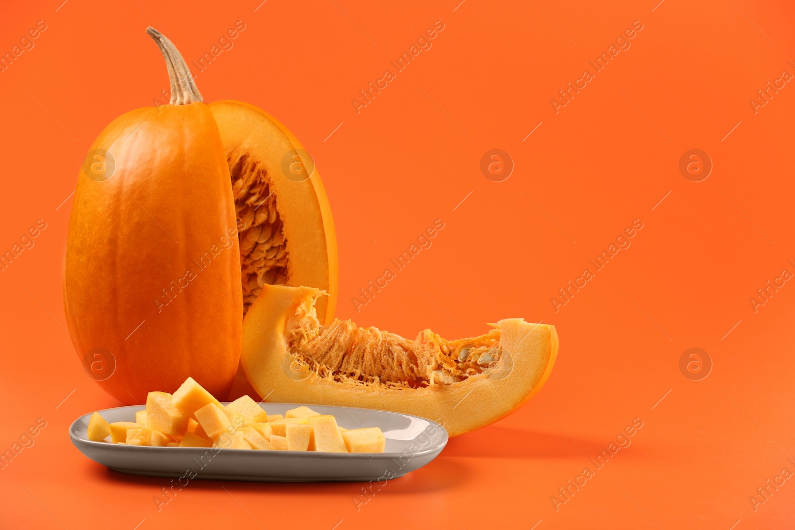 Photo of Cut fresh ripe pumpkin on orange background, space for text