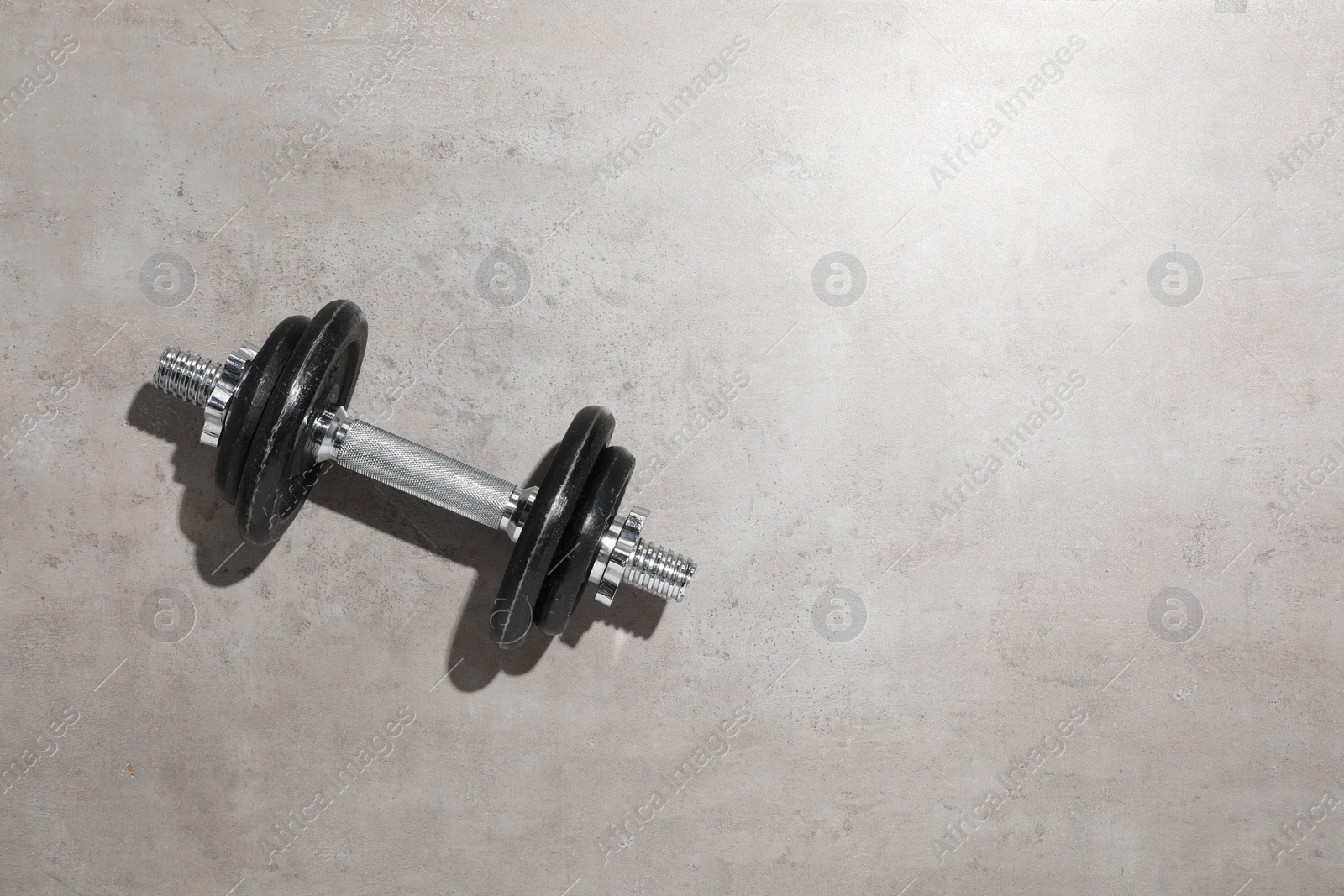 Photo of One barbell on grey floor, top view. Space for text