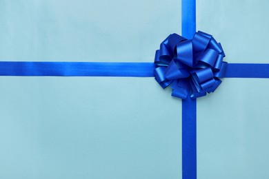 Photo of Ribbons with bow on light blue background, top view. Space for text