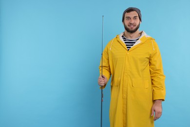 Fisherman with fishing rod on light blue background, space for text