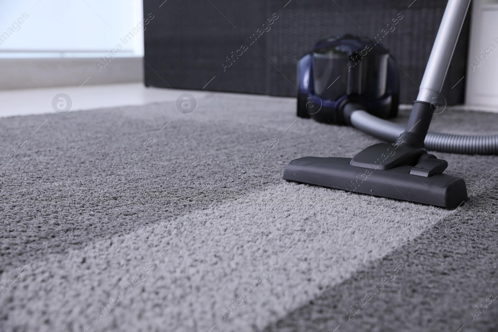 Photo of Modern vacuum cleaner on carpet. Space for text