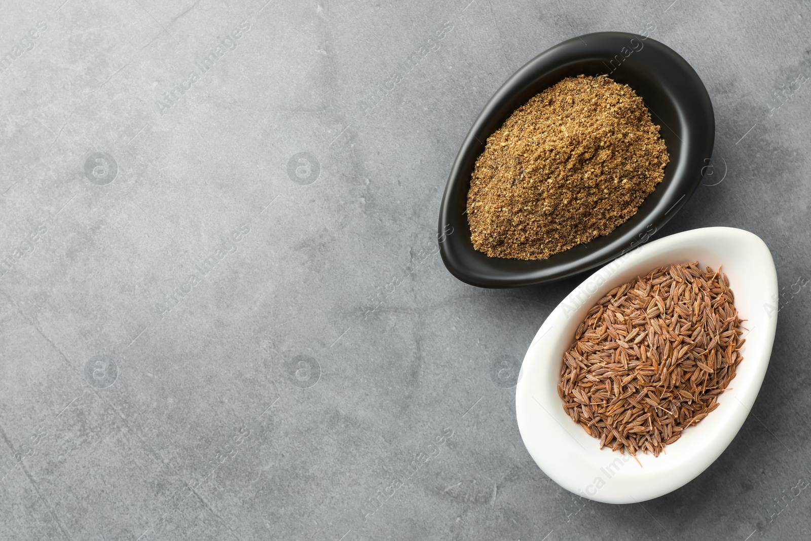 Photo of Caraway (Persian cumin) powder and dry seeds on gray table, top view. Space for text