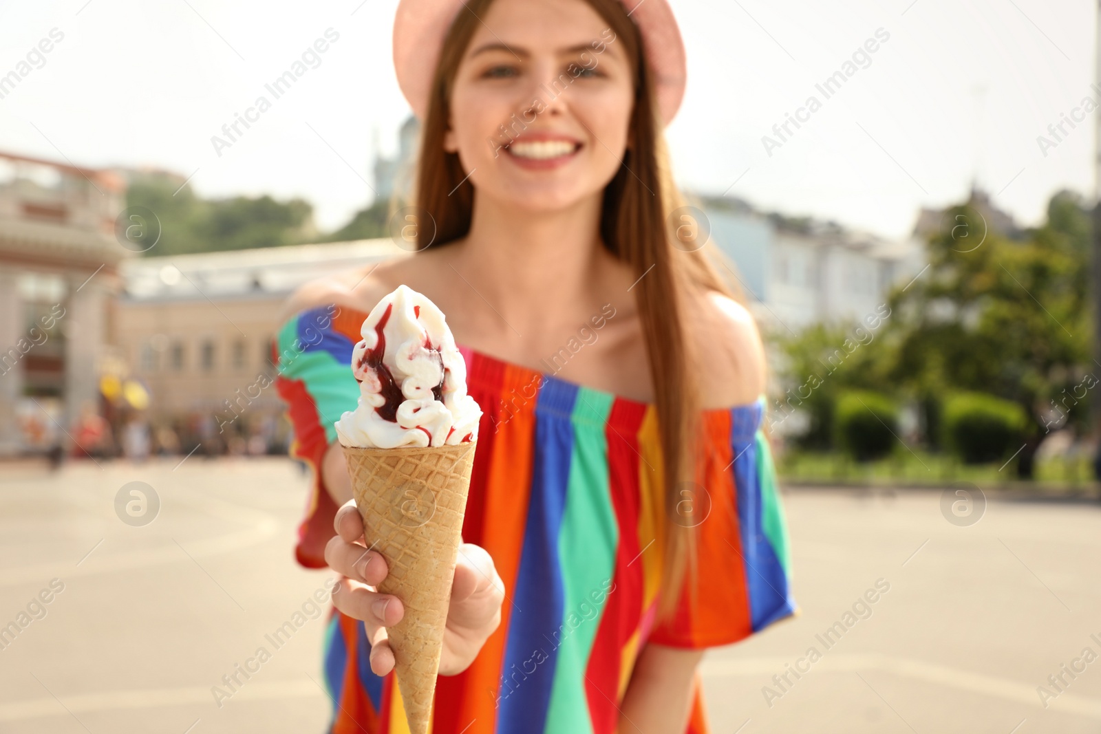 Photo of Young happy woman with ice cream cone on city street